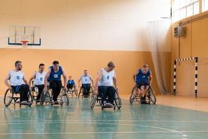 les vétérans de la guerre handicapés s'opposent à des équipes de basket-ball en fauteuil roulant photographiées en action tout en jouant un match important dans une salle moderne. photo