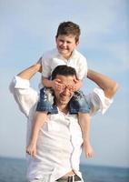 heureux père et fils s'amusent et profitent du temps sur la plage photo