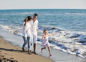 jeune famille heureuse s'amuser sur la plage photo