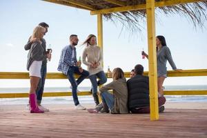 groupe d'amis s'amusant le jour de l'automne à la plage photo