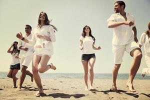 groupe de personnes heureuses s'amuser et courir sur la plage photo