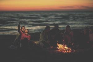 un groupe d'amis profitant d'un feu de joie sur la plage photo