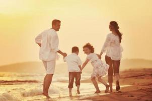 jeune famille heureuse s'amuser sur la plage au coucher du soleil photo