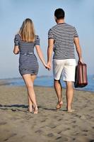 couple sur la plage avec sac de voyage photo