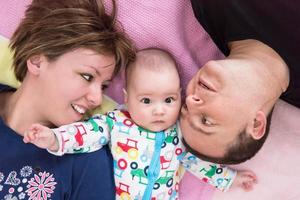 vue de dessus d'un jeune couple souriant allongé avec son bébé photo