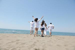 groupe de personnes heureuses s'amuser et courir sur la plage photo