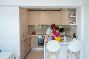 une petite fille amusante jouant avec de la pâte sur ses mains apprenant à pétrir aide une maman adulte dans la cuisine, une petite fille mignonne et heureuse et une maman parent s'amusent à cuisiner des biscuits. photo