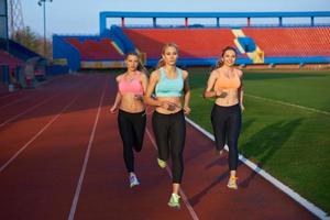 groupe de femmes athlètes courant sur une piste de course d'athlétisme photo