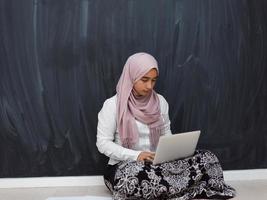 adolescent arabe avec hijab assis sur le sol de la maison et regardant des cours en ligne pendant la pandémie de coronavirus. mise au point sélective photo