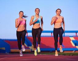 groupe de femmes athlètes courant sur une piste de course d'athlétisme photo