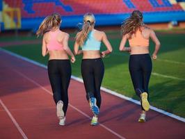 groupe de femmes athlètes courant sur une piste de course d'athlétisme photo