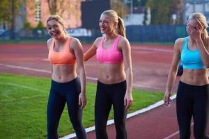 groupe de femmes athlètes courant sur une piste de course d'athlétisme photo