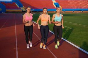 groupe de femmes athlètes courant sur une piste de course d'athlétisme photo