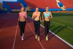 groupe de femmes athlètes courant sur une piste de course d'athlétisme photo