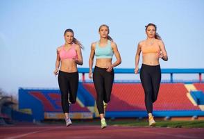 groupe de femmes athlètes courant sur une piste de course d'athlétisme photo