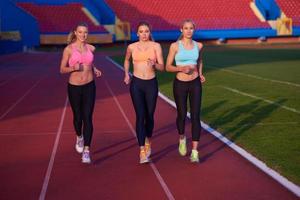 groupe de femmes athlètes courant sur une piste de course d'athlétisme photo