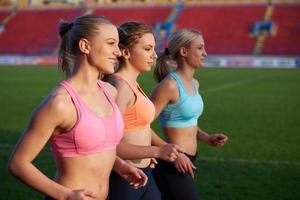 groupe de femmes athlètes courant sur une piste de course d'athlétisme photo