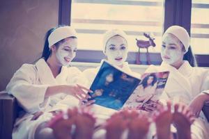 enterrement de vie de jeune fille au spa, filles avec masque facial lisant un magazine photo