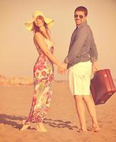 couple sur la plage avec sac de voyage photo