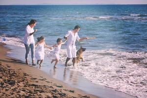 famille heureuse jouant avec un chien sur la plage photo