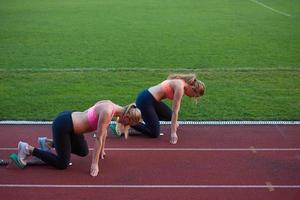 groupe de femmes athlètes courant sur une piste de course d'athlétisme photo