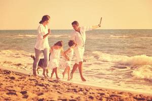 famille heureuse jouant avec un chien sur la plage photo