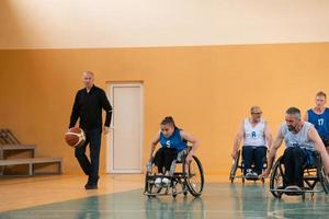 les vétérans de la guerre handicapés s'opposent à des équipes de basket-ball en fauteuil roulant photographiées en action tout en jouant un match important dans une salle moderne. photo