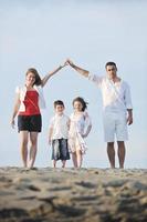 famille sur la plage montrant le signe de la maison photo