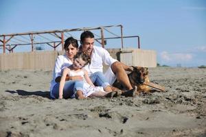 famille heureuse jouant avec un chien sur la plage photo