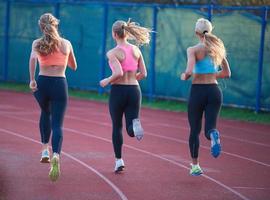 groupe de femmes athlètes courant sur une piste de course d'athlétisme photo