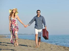 couple sur la plage avec sac de voyage photo