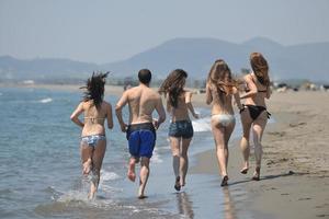 groupe de personnes heureuses s'amuser et courir sur la plage photo