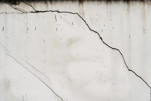 maison brisée. fissure du béton. intérieur du bâtiment endommagé par l'eau. grand mur de béton blanc fissuré photo