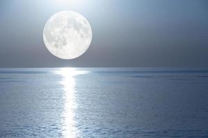 pleine lune avec un chemin lunaire reflété dans le miroir de la mer. photo