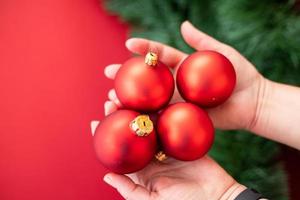 boules de sapin de noël rouges tenues dans les mains. concept de joyeux noël. photo