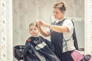 coiffeur coupant les cheveux du petit garçon. photo