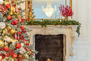 salle intérieure décorée de noël classique, arbre du nouvel an avec des décorations rouges et or. appartement de design d'intérieur de style classique blanc moderne avec cheminée et arbre de noël. réveillon de noël à la maison. photo