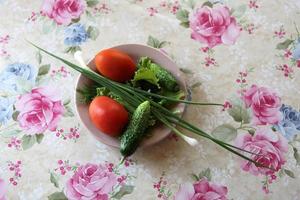 tomate et concombre sur une assiette avec des verts et des oignons verts photo