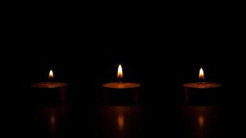 Trois bougies de cire allumées sur fond noir photo