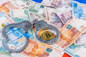 bitcoin shiner enchaîné avec des menottes sur fond de monnaie roubles papier russe photo