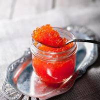caviar de saumon rouge dans un bocal en verre et une cuillère photo