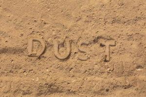 le mot poussière en relief sur la surface de la route poussiéreuse dans une perspective à plat photo