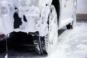 une voiture recouverte de mousse de savon pendant le lavage à l'intérieur - vue rapprochée en position basse de l'arrière avec mise au point sélective photo