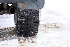 une photo sans fioritures de la roue de voiture d'hiver avec des pointes métalliques sur la neige en gros plan