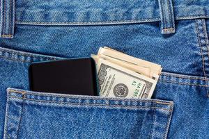 billets en dollars américains et smartphone dans la poche arrière gauche du jean bleu. photo