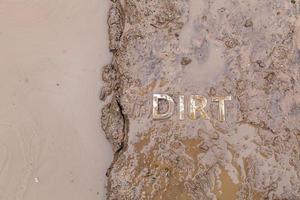 le mot boue imprimé sur la surface du chemin de terre humide - gros plan avec mise au point sélective photo