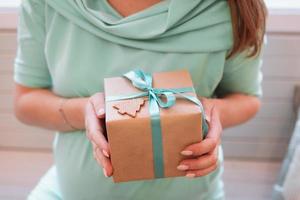 femme enceinte en robe bleue tient une boîte-cadeau avec des décorations de noël. mode de vie enceinte. photo