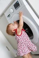 enfant avec machine à laver. petite fille aide aux tâches familiales. photo