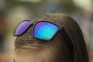 verres avec des gouttes de pluie. lunettes sur la tête. verre bleu. verre humide. tête de fille. photo