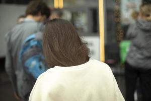 cheveux des filles à l'arrière. fille en ligne. brune dans la rue. pull blanc. photo